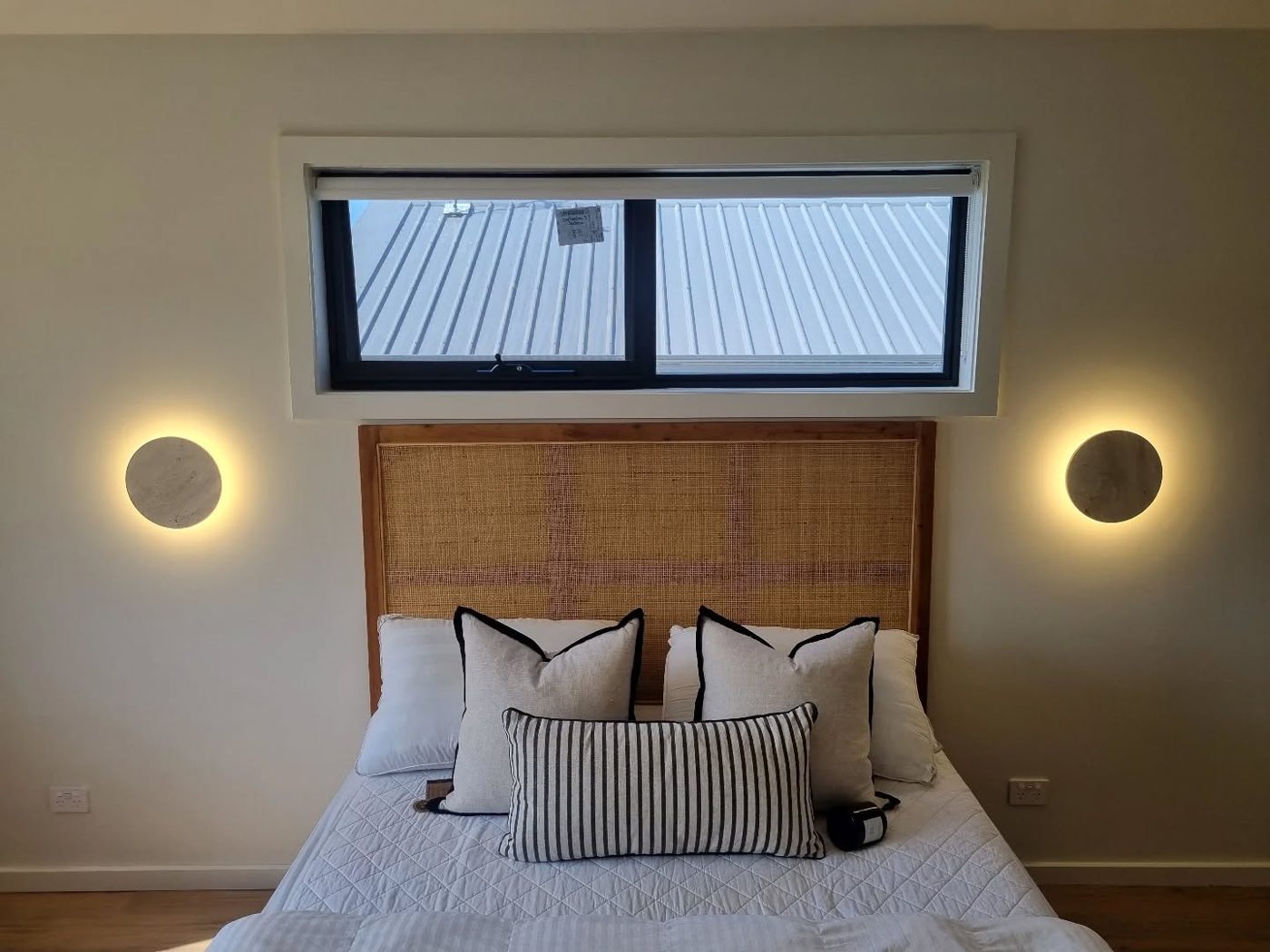 Travertine stone bedside wall sconces flanking a bed