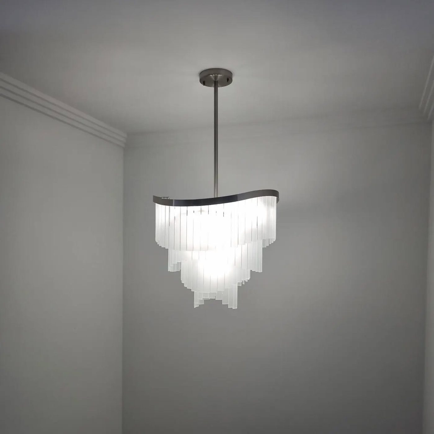 Tiered frosted glass pendant chandelier installed in a corner