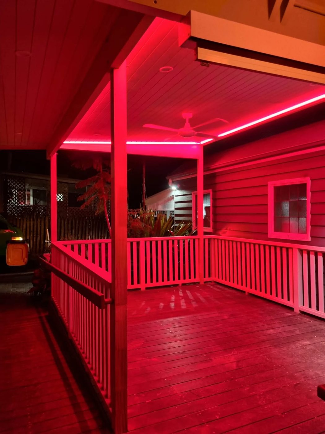 Outdoor entertaining deck with LED strip lighting and ceiling fan at night