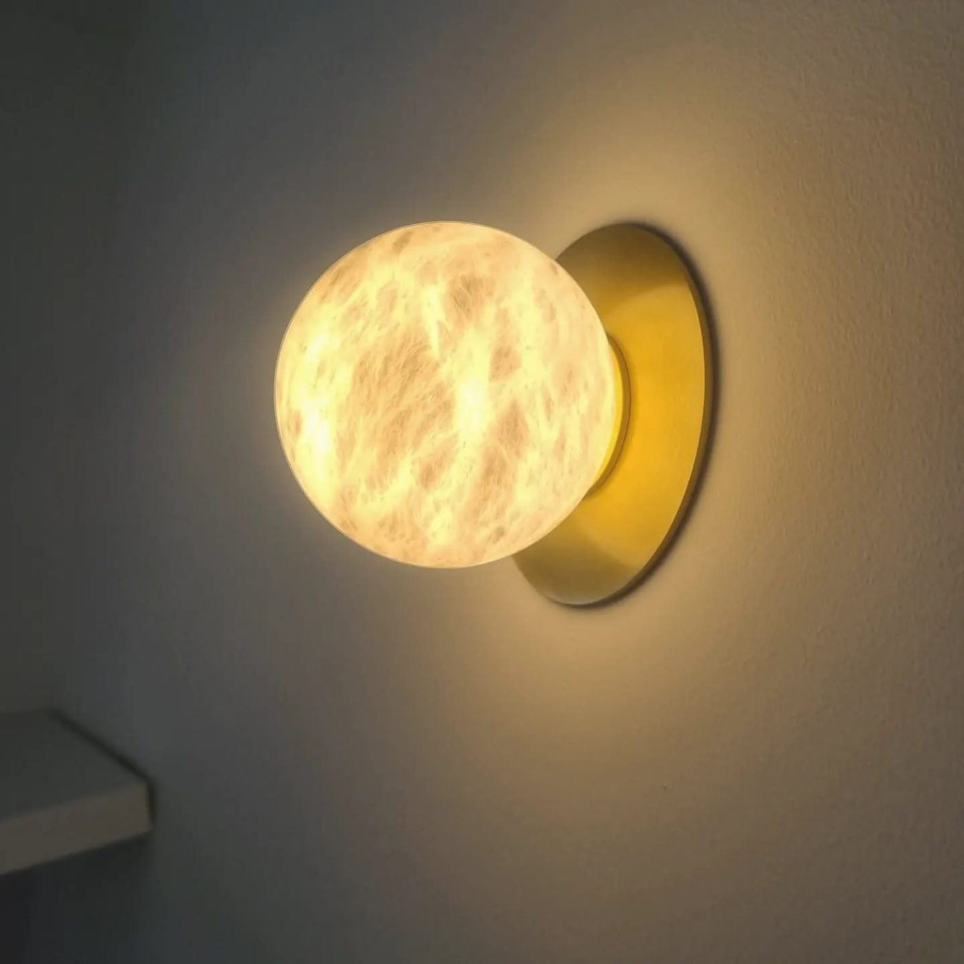Alabaster moon wall light with brass backplate, installed and lit
